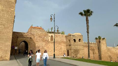       Visitors walk along the fortified walls and palm-lined street of Rabat
  