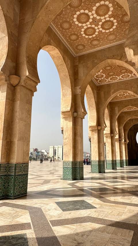       Stone arches of Hassan II Mosque colonnade frame view of Casablanca skyline
  