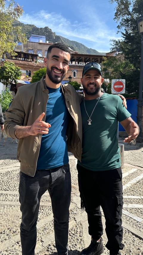       Two smiling friends pose arm-in-arm on a sunny street
  