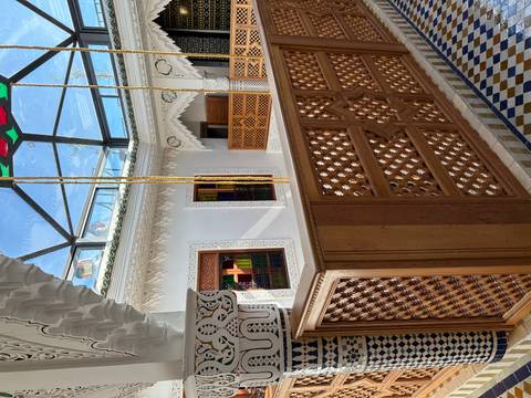       Elegant riad atrium with carved plaster, stained glass skylight and wooden balustrade
  