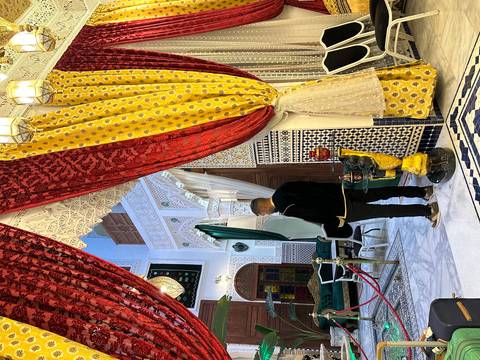       Opulent riad interior with patterned tiles, velvet drapes and hanging lanterns
  