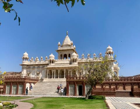       White marble memorial Jaswant Thada with domes and steps against blue sky
  