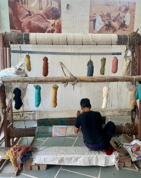       Craftsman weaves colorful carpet threads on a traditional loom
  
