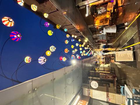       Night street scene decorated with colorful hot-air-balloon lanterns after rain.
  