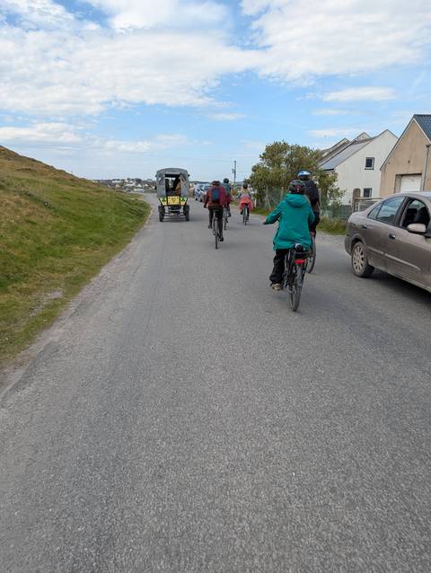       Cyclists and a horse cart sharing narrow rural road on Irish island.
  