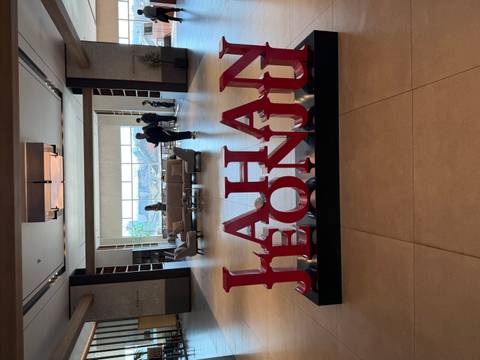       Hotel lobby with large JEONJU sign in red letters and guests milling around.
  