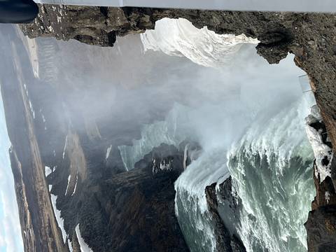       Powerful Gullfoss waterfall cascades into a mist-filled canyon amid snowy edges.
  