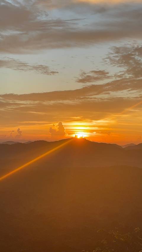       Spectacular sunrise casting golden rays over layered mountain ridges
  