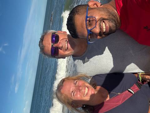       Happy trio smiling for a beachside selfie with crashing waves behind
  