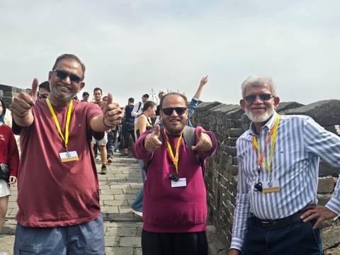       Three travellers giving enthusiastic thumbs-up atop the Great Wall
  