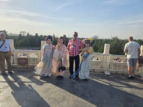       Tourist posing with costumed locals on a viewpoint overlooking a park
  
