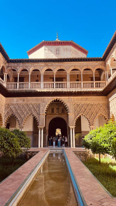       Ornate Moorish courtyard façade with intricate arches and carved stone details.
  