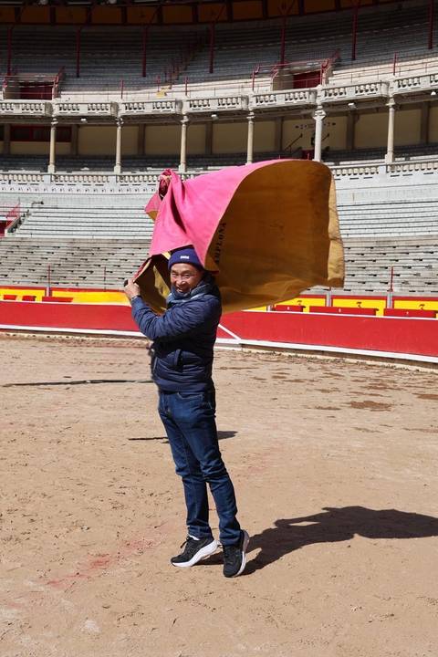       Visitor playfully waves a bullfighting cape inside Pamplona's empty arena.
  