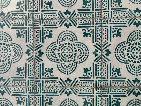       Close-up of ornate green and white Portuguese azulejo tile pattern.
  