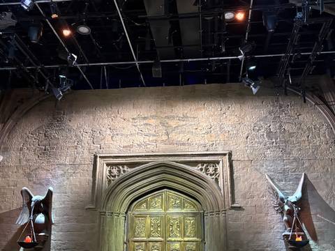       Stone wall with ornate gothic doorway beneath stage lighting rigs in a studio set
  