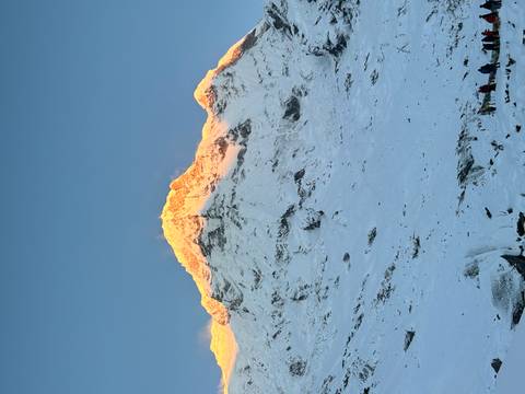       Snow-covered Himalayan summit glowing orange in first light against a clear blue sky.
  