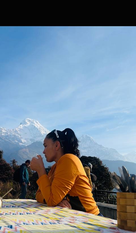       Profile of a female trekker with ponytail against a backdrop of two snow-draped Himalayan peaks.
  