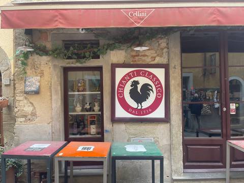       Street façade with a Chianti Classico rooster logo sign framed by rustic stone walls and ivy.
  