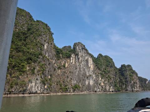      Dramatic limestone karst cliffs rising from turquoise waters under a clear blue sky.
  