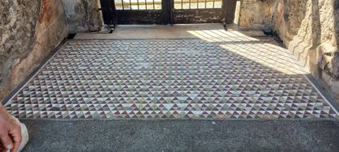       Ancient geometric mosaic floor of multicoloured stone triangles at an archaeological site.
  