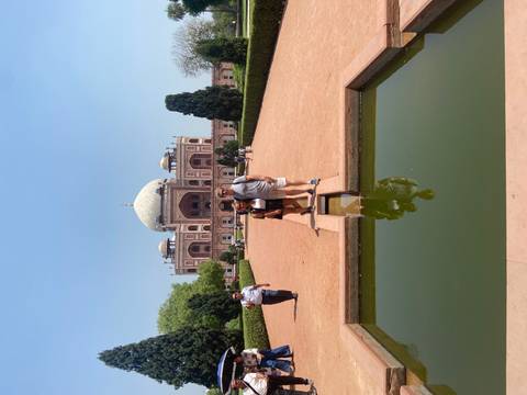       Couple standing in front of Humayun's Tomb with symmetrical Mughal gardens and clear blue sky.
  