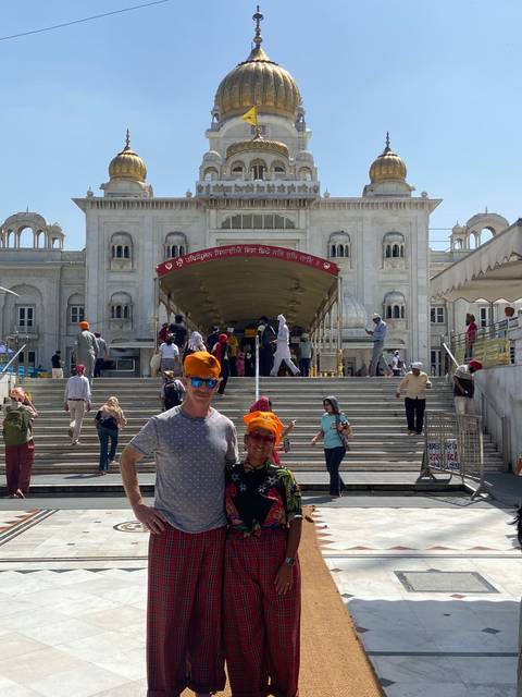       Visitors wearing orange head coverings stand on the steps of a white marble Sikh temple in Delhi.
  