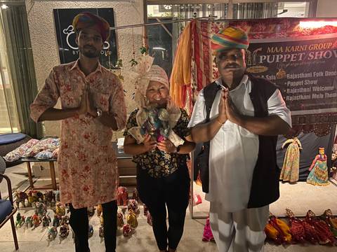       Traveler poses with two local performers at a nighttime Rajasthani puppet show.
  