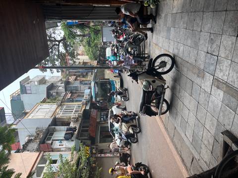       Bustling Hanoi street scene with scooters, a coach bus and shop-houses lining the road.
  