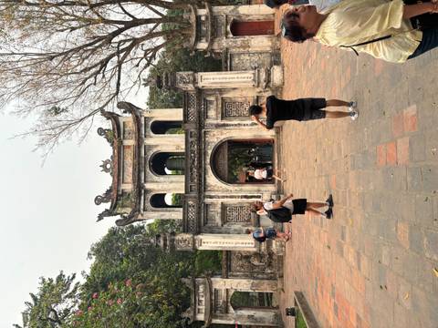       Travelers photograph the historic main gate of the Temple of Literature with leafless trees overhead.
  