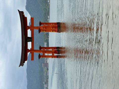       Famed orange torii gate of Itsukushima Shrine rises from calm sea waters.
  