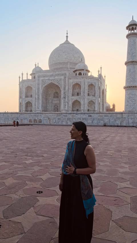       Close-up of a traveler smiling with the marble walls of the Taj Mahal at sunset.
  