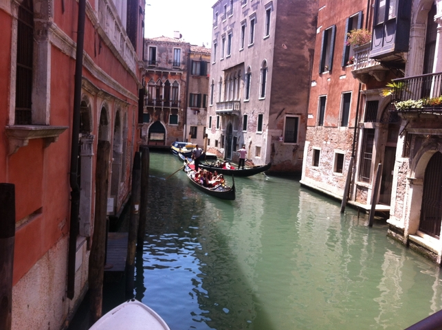 Gondolas on a canal in Venice with people.