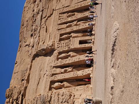       Tourists exploring the monumental rock-cut statues of Abu Simbel temple complex
  