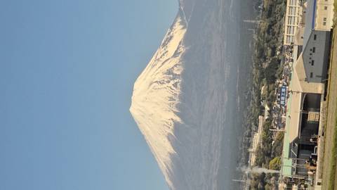       Snow-capped Mount Fuji rises above a clear blue sky with a town in the foreground.
  