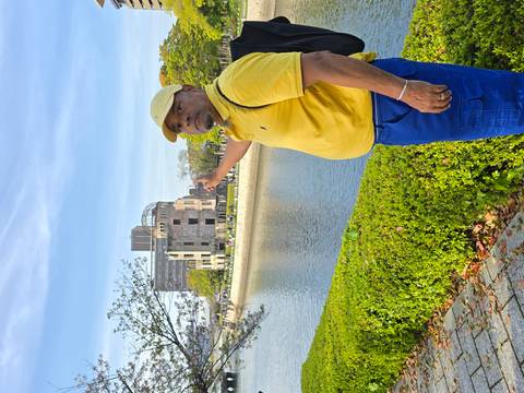       A traveler in yellow points across the river toward the Hiroshima A-Bomb Dome building.
  