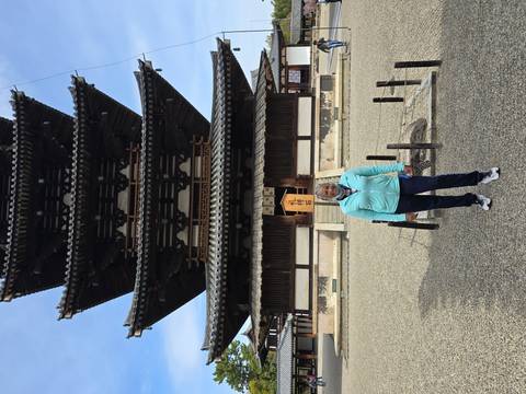       Traveler stands before a five-story wooden pagoda in an open courtyard on a sunny day.
  