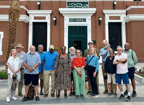       A tour group poses in front of the historic Old Cataract Hotel entrance.
  