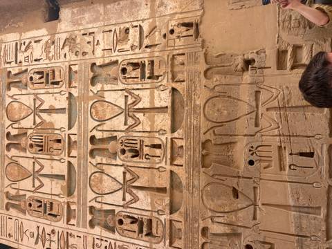       Detailed hieroglyphs and Ankh symbols carved into a sandstone temple wall.
  