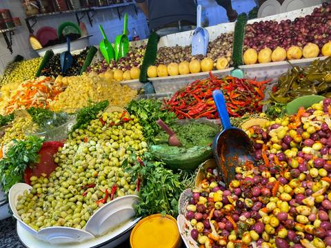       Colorful market stall overflowing with olives, peppers and herbs
  