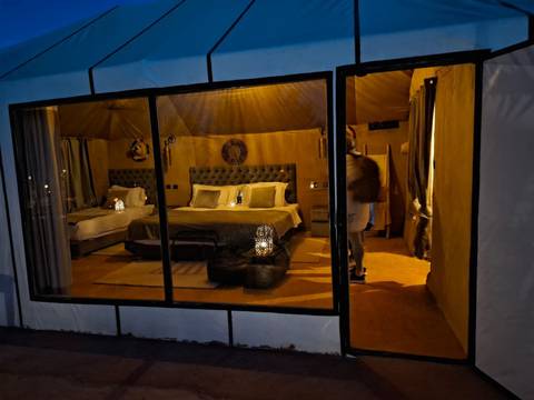       Chic desert glamping tent interior with twin beds, lanterns and warm golden lighting.
  