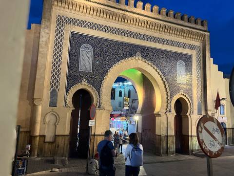       Evening light glows on the ornate tiled arch of Fes’s Bab Boujloud gate as visitors enter the medina.
  