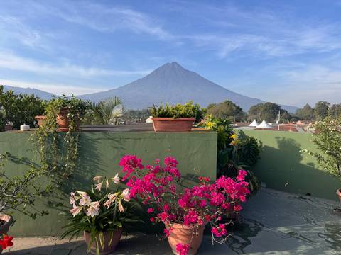       Bright bougainvillea blooms on a rooftop garden framing Volcán de Agua rising majestically over Antigua.
  
