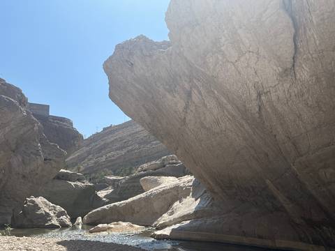       Steep limestone canyon walls under a bright blue sky in Oman’s wadi region.
  