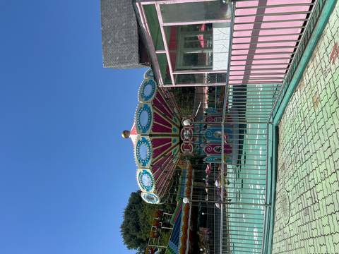       Colorful empty swing carousel ride in an amusement park on a clear blue-sky day.
  