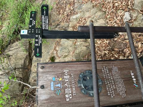       Trail signboards and information panel on a forested mountainside indicating direction to Geumunsa Temple.
  