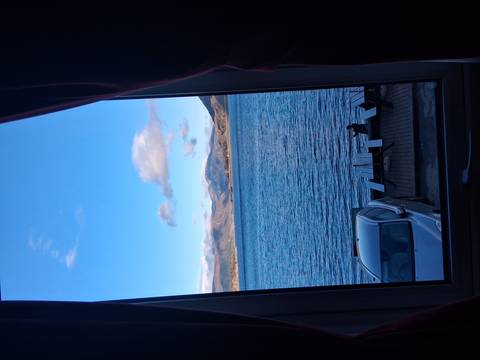       Lake and mountains viewed through a hotel room window with car parked below.
  