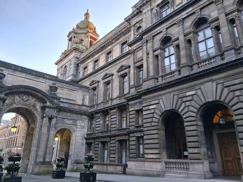       Elegant Victorian stone architecture with grand arch and clock tower in Glasgow city centre.
  