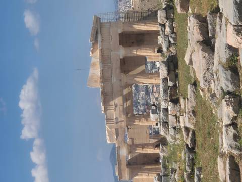       Partial view of the Parthenon columns overlooking Athens cityscape under a bright blue sky.
  