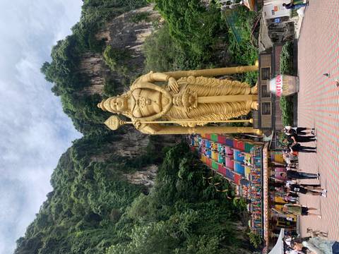       Crowds ascend the colorful steps toward the giant golden statue at Batu Caves.
  