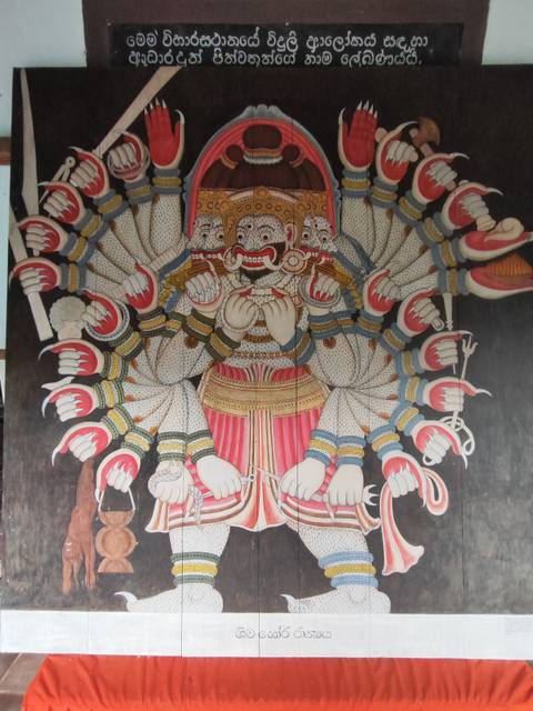       Detailed mural of a many-headed demon king holding weapons, rich in traditional Sri Lankan art style.
  
